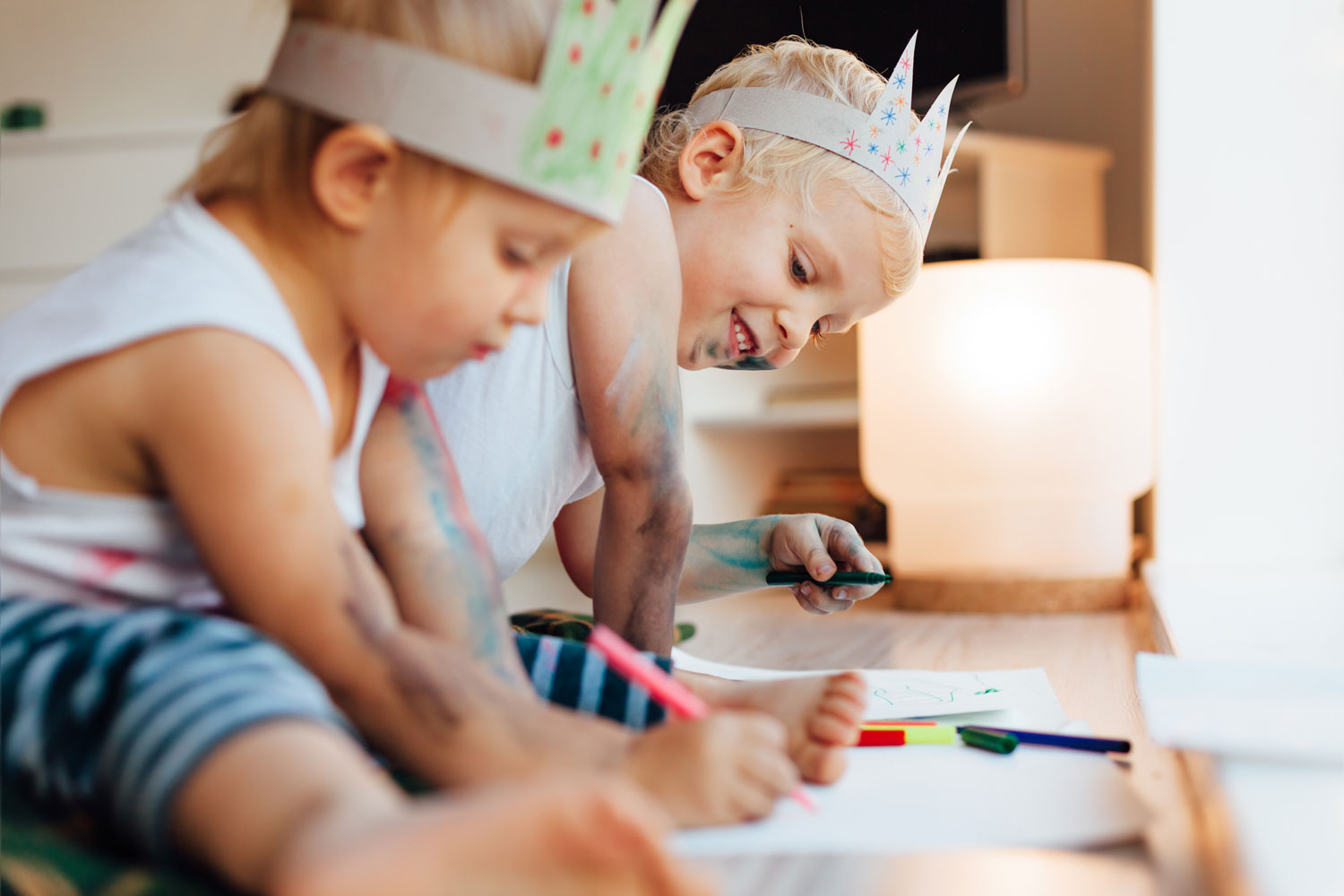 Zwei Kinder sitzen am Boden und malen mit Buntstiften während des Babysitter Kurses in München
