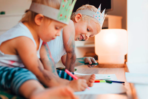 Zwei Kinder sitzen am Boden und malen mit Buntstiften während des Babysitter Kurses in München